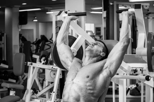 Muskulöser Mann, der im Fitnessstudio mit Gewichten trainiert. Mann macht Übungen. — Stockfoto