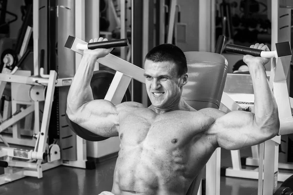 Svalnatý muž, pracuje se s váhami v tělocvičně. Člověk dělá cvičení. — Stock fotografie