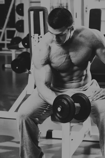 Bodybuilder makes exercise with dumbbells at the gym. — Stock Photo, Image