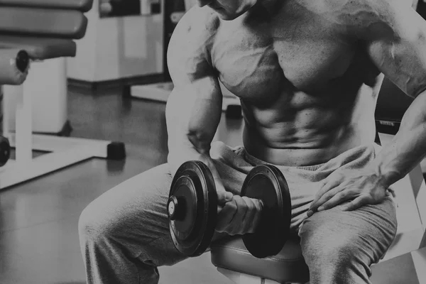 Vücut geliştirmeci yapar egzersiz jimnastik salonu dumbbells ile. — Stok fotoğraf