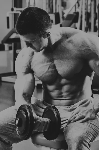 Bodybuilder makes exercise with dumbbells at the gym. — Stock Photo, Image