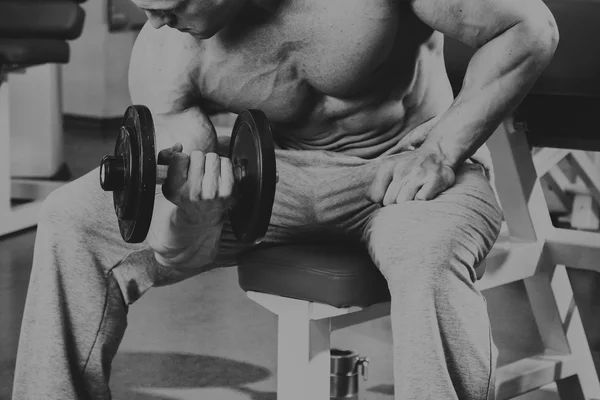 Vücut geliştirmeci yapar egzersiz jimnastik salonu dumbbells ile. — Stok fotoğraf