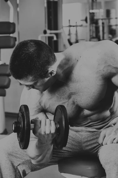 Vücut geliştirmeci yapar egzersiz jimnastik salonu dumbbells ile. — Stok fotoğraf