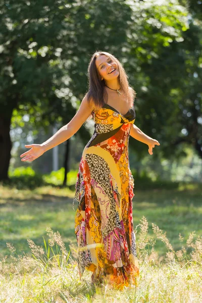 Una chica joven y atractiva en hermoso vestido de verano en medio de prados soleados. Chica alegre tomando el sol en los cálidos rayos del sol de verano. Hermosa imagen de una chica despreocupada. Fotos para revistas , —  Fotos de Stock