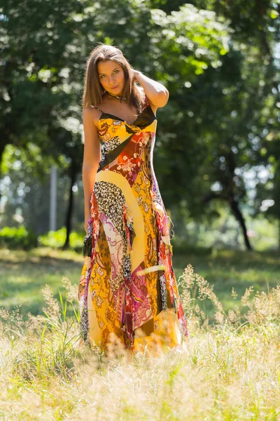 Una chica joven y atractiva en hermoso vestido de verano en medio de prados soleados. Chica alegre tomando el sol en los cálidos rayos del sol de verano. Hermosa imagen de una chica despreocupada. Fotos para revistas , — Foto de Stock