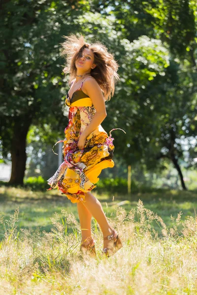 Una ragazza giovane e attraente in bel vestito estivo in mezzo a prati soleggiati. Ragazza allegra crogiolarsi nei caldi raggi del sole estivo. Bella immagine di una ragazza spensierata. Foto per riviste , — Foto Stock