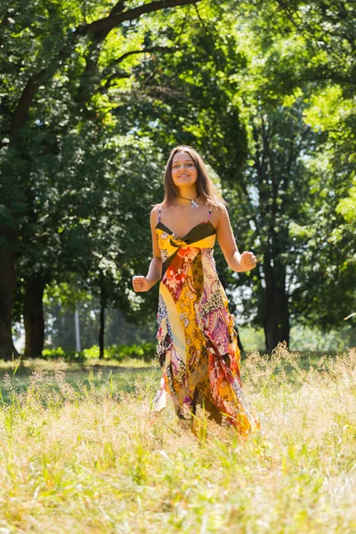 Ein junges und attraktives Mädchen in schönem Sommerkleid inmitten sonniger Wiesen. fröhliches Mädchen, das sich in den warmen Strahlen der Sommersonne sonnt. schöne Bild eines unbeschwerten Mädchens. Fotos für Zeitschriften, — Stockfoto