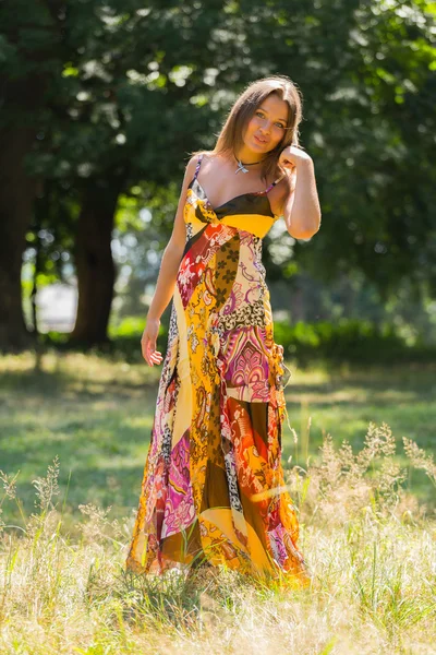 Uma menina jovem e atraente em belo vestido de verão no meio de prados ensolarados. Menina alegre se aquecendo nos raios quentes do sol de verão. Imagem bonita de uma menina despreocupada. Fotos para revistas , — Fotografia de Stock