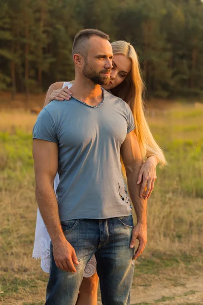 Biker and beautiful girl in a field on a motorcycle. — Stock Photo, Image