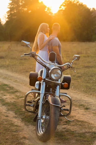 Biker et belle fille dans un champ sur une moto . — Photo