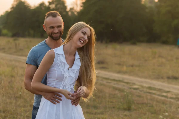 Biker and beautiful girl in a field on a motorcycle. — Stock Photo, Image