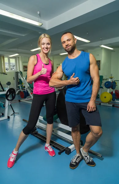 Young couple at a joint training session in the gym. Mutual assistance in carrying out exercises. Proper exercise. Photos for sporting and social magazines, posters and websites. — Stock Photo, Image