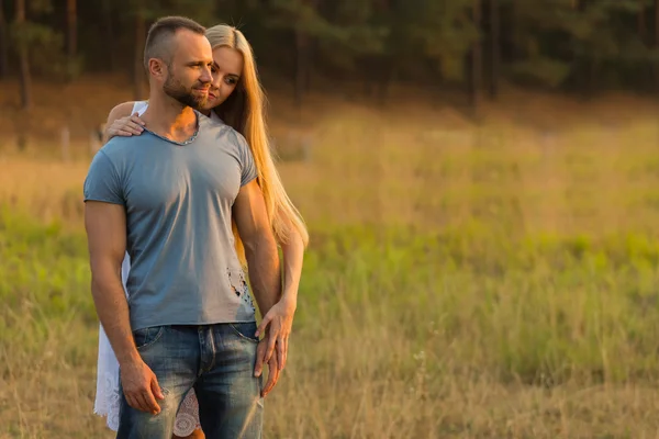 Biker and beautiful girl in a field on a motorcycle. — Stock Photo, Image