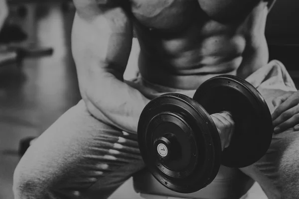 Vücut geliştirmeci yapar egzersiz jimnastik salonu dumbbells ile. — Stok fotoğraf