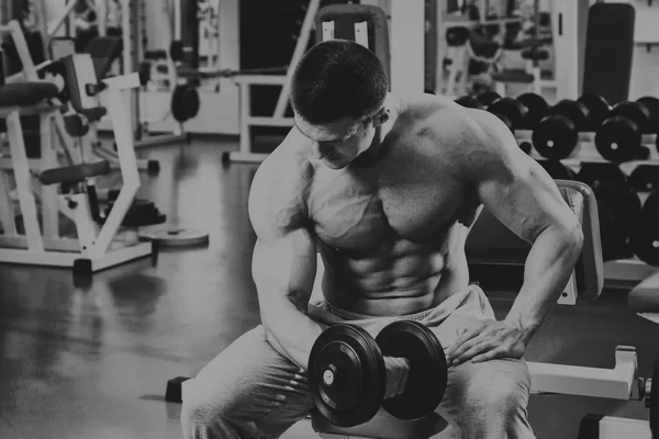 Vücut geliştirmeci yapar egzersiz jimnastik salonu dumbbells ile. — Stok fotoğraf