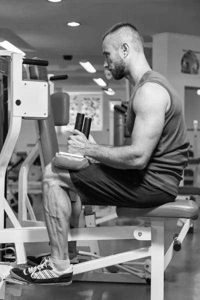 Homem a fazer exercícios nas pernas, exercícios no simulador. Esportes, estilo de vida saudável . — Fotografia de Stock