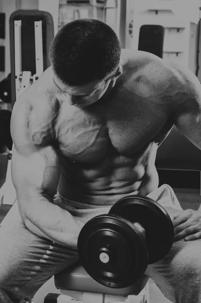 Bodybuilder makes exercise with dumbbells at the gym. — Stock Photo, Image