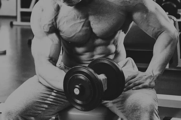 Bodybuilder makes exercise with dumbbells at the gym. — Stock Photo, Image