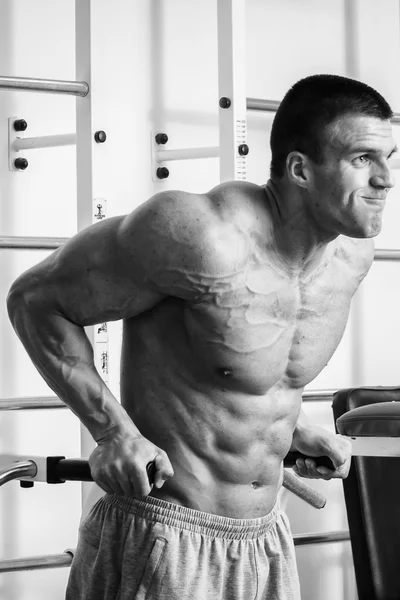 Uomo muscolare che lavora con i pesi in palestra. L'uomo fa esercizi . — Foto Stock