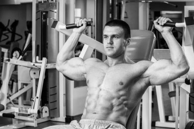 Kaslı adam spor salonunda ağırlık ile çalışma dışarı. Adam egzersizleri yapar.