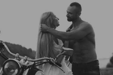 Siyah ve beyaz fotoğraf motorcu çift bir motosiklet alanında.