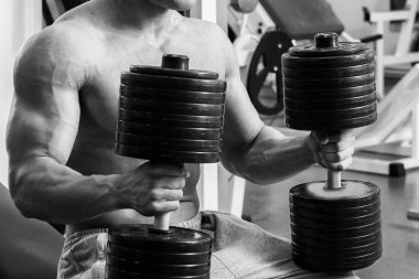 Vücut geliştirme dumbbells ile. Husky büyük bir dumbbell elinde tutar. Spor, vücut geliştirme, sağlıklı yaşam tarzı.