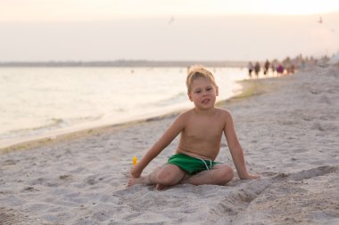 Sahilde erkek şort. Deniz kum ile oynayan çocuk. Sevinç ve eğlenceli çocuklar için. Güzel sıcak bir gün. Çocuk dergi ve Web siteleri için fotoğraf.