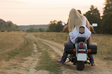 Yeni evliler orta alanın bir motosiklet yolda. Mutlu çifte bir motosiklet üzerinde seyahat.