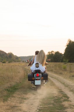 Yeni evliler orta alanın bir motosiklet yolda. Mutlu çifte bir motosiklet üzerinde seyahat.