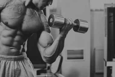 Vücut geliştirmeci yapar egzersiz jimnastik salonu dumbbells ile.