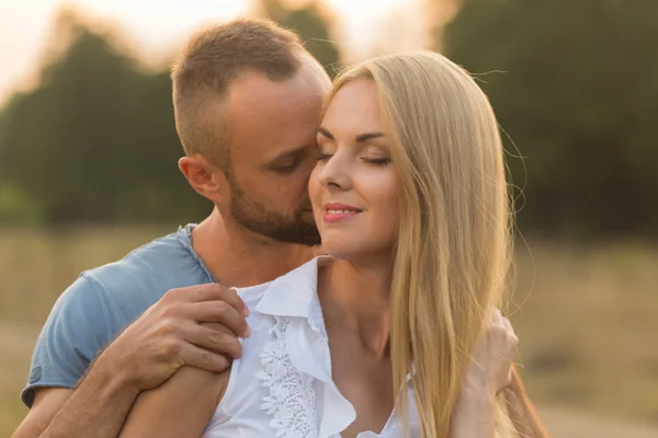 Man och kvinna omfamnar ömt i fältet. Kärlek och uppriktiga känslor. — Stockfoto