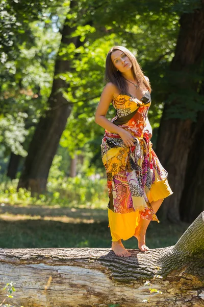 Una chica joven y atractiva en hermoso vestido de verano en medio de prados soleados. Chica alegre tomando el sol en los cálidos rayos del sol de verano. Hermosa imagen de una chica despreocupada . — Foto de Stock