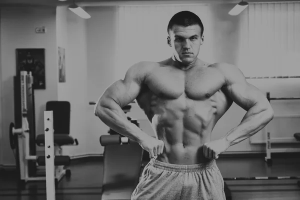 Un uomo bello, atletico e sicuro di se 'in palestra. posa bodybuilding — Foto Stock