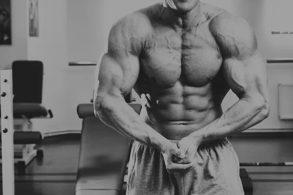 Un uomo bello, atletico e sicuro di se 'in palestra. posa bodybuilding — Foto Stock