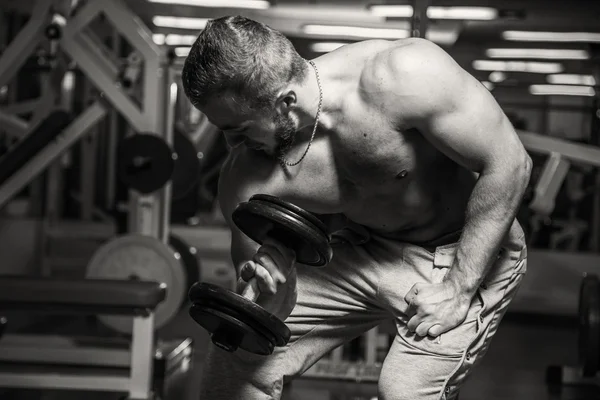 Man op de sportschool. Man maakt oefeningen halters. Sport, voeding, halters, spanning, oefening - het concept van een gezonde levensstijl. Artikel over fitness en sport. — Stockfoto