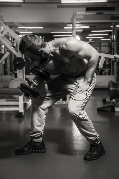 Man op de sportschool. Man maakt oefeningen halters. Sport, voeding, halters, spanning, oefening - het concept van een gezonde levensstijl. Artikel over fitness en sport. — Stockfoto