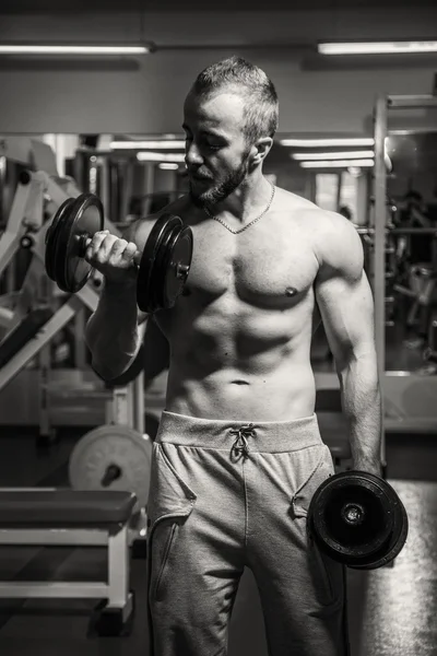 Man at the gym. Man makes exercises dumbbells. Sport, power, dumbbells, tension, exercise - the concept of a healthy lifestyle. Article about fitness and sports. — Stock Photo, Image