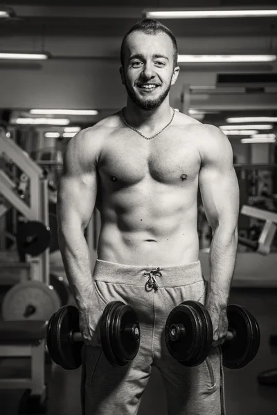 Hombre en el gimnasio. El hombre hace ejercicios de pesas. El deporte, el poder, las pesas, la tensión, el ejercicio - el concepto de un estilo de vida saludable. Artículo sobre fitness y deportes . —  Fotos de Stock