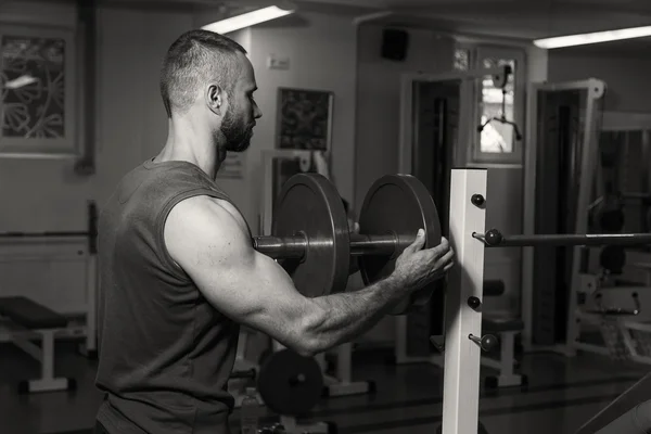 Krachttraining met halters. Husky houdt een grote halter in de hand. Sport, bodybuilding, gezonde levensstijl. — Stockfoto