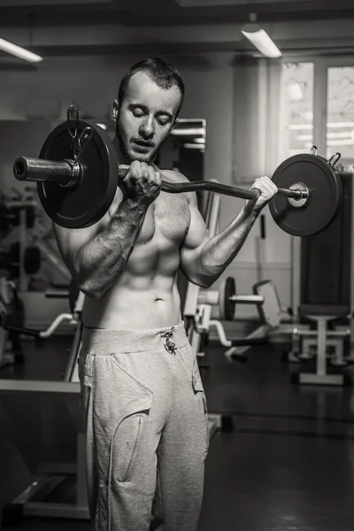 Hombre musculoso haciendo ejercicio con pesas en el gimnasio. El hombre hace ejercicios . — Foto de Stock