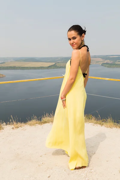 Porträtt av flickan mot bakgrund av ett naturskönt landskap. Flicka i naturen i en vacker gul klänning. — Stockfoto