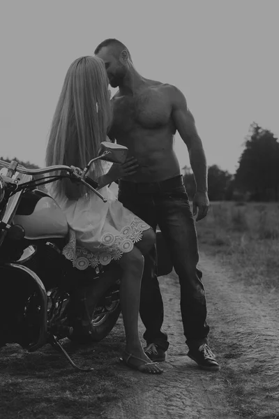 Black and white photo biker couple on a motorcycle in the field. — Stock Photo, Image