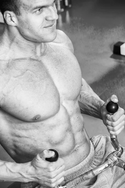 Homme musclé travaillant avec des poids dans la salle de gym. L'homme fait des exercices . — Photo