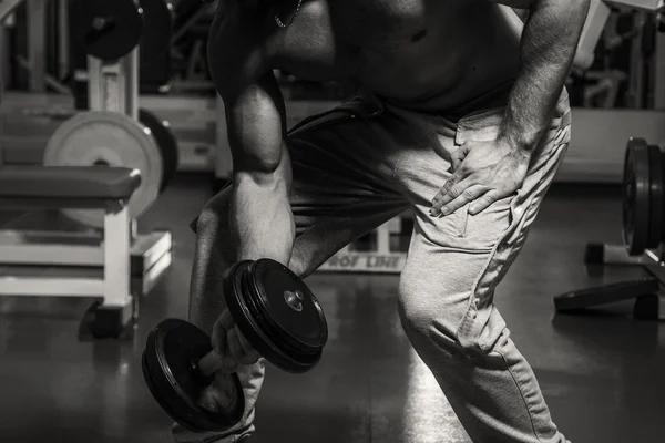 Hombre en el gimnasio. El hombre hace ejercicios de pesas. El deporte, el poder, las pesas, la tensión, el ejercicio - el concepto de un estilo de vida saludable. Artículo sobre fitness y deportes . —  Fotos de Stock