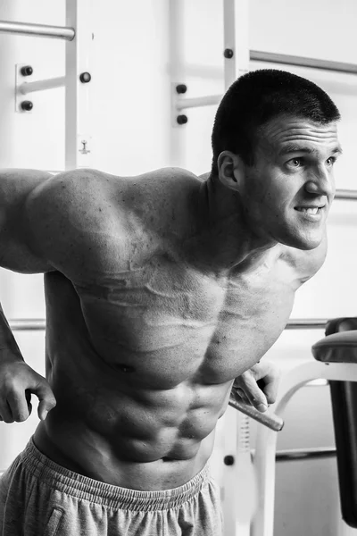 Homem musculoso a exercitar-se com pesos no ginásio. Homem faz exercícios . — Fotografia de Stock