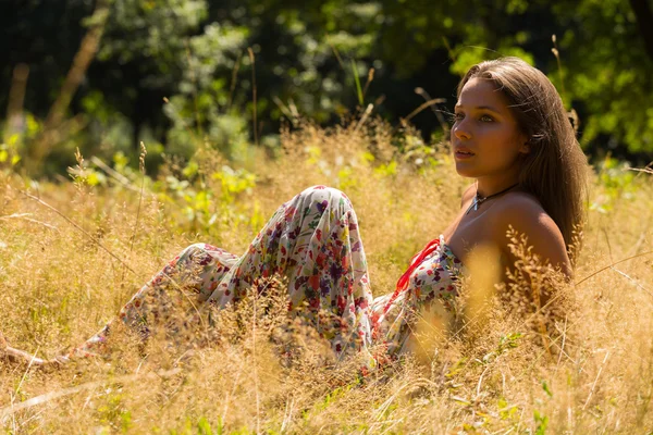 Młode i atrakcyjne dziewczyny w piękne lato sukienka środku słonecznej łąki. Wesoła dziewczyna, pławiąc się w ciepłe promienie słońca latem. Piękny obraz beztroski dziewczynka. — Zdjęcie stockowe