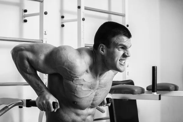 Muskulöser Mann, der im Fitnessstudio mit Gewichten trainiert. Mann macht Übungen. — Stockfoto