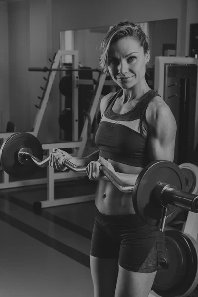 Meisje pompt de grote spiergroepen in de sportschool. Krachttraining. Vrouwelijke fitness. Sterke meisje. — Stockfoto