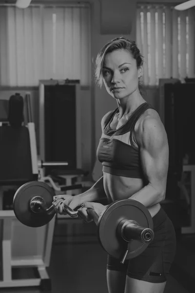 Meisje pompt de grote spiergroepen in de sportschool. Krachttraining. Vrouwelijke fitness. Sterke meisje. — Stockfoto