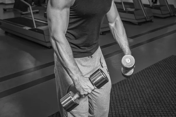 Um homem no ginásio. O homem faz exercícios halteres. Esporte, poder, halteres, tensão, exercício - o conceito de um estilo de vida são. Artigo sobre fitness e esportes . — Fotografia de Stock